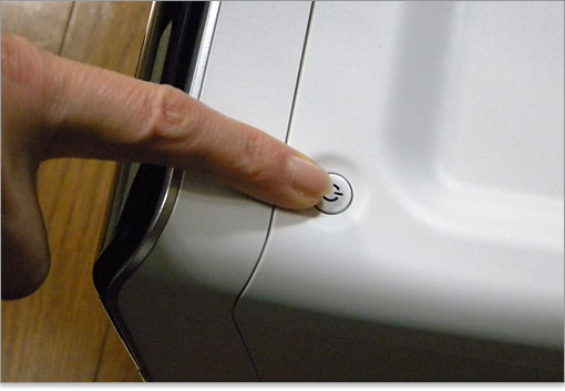 小柄な女性が電源ボタンに指を置いたところ。